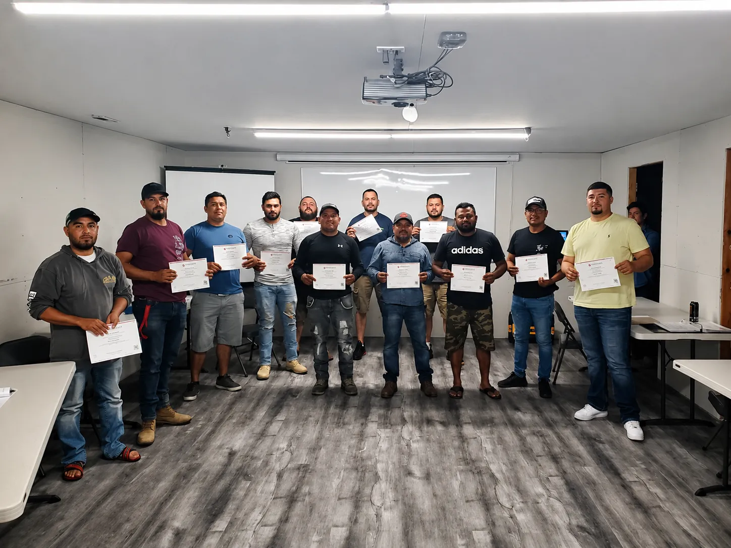 A class of workers holding their First Aid & CPR safety certificates after an ACMAN Solutions training course